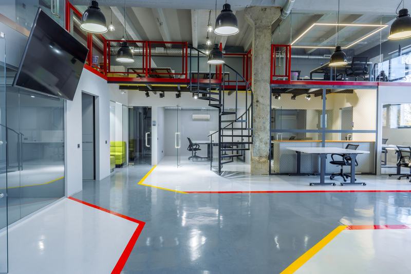 Open commercial interior with a red spiral stair and a glossy gray floor with red and yellow markings